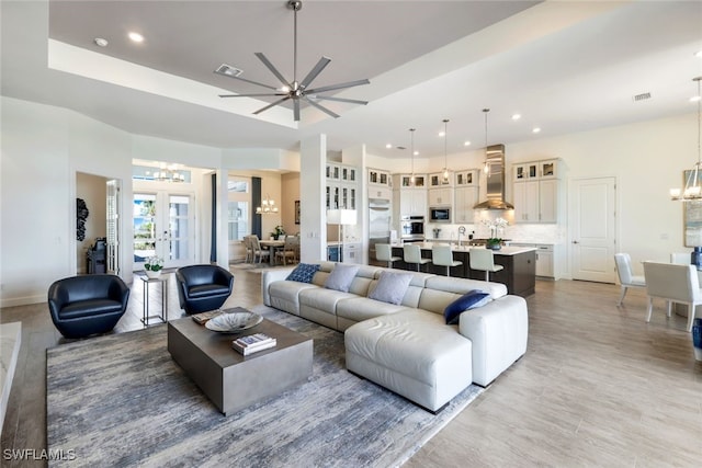 living room featuring french doors and ceiling fan with notable chandelier