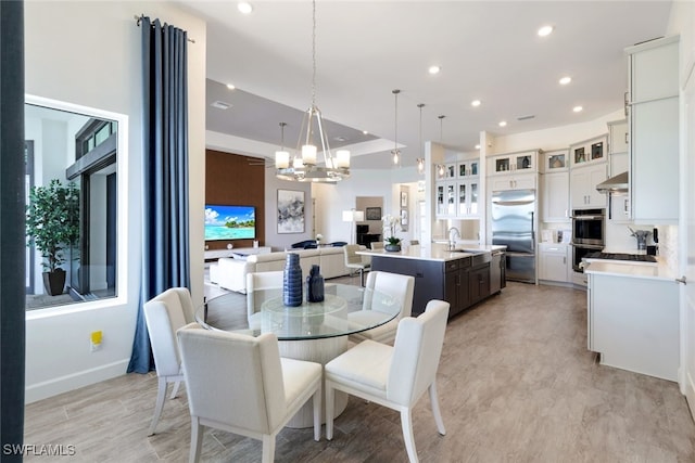 dining area with a notable chandelier, light wood-type flooring, and sink