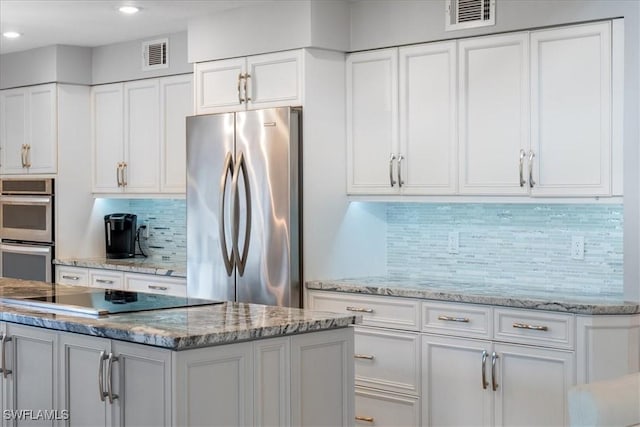 kitchen featuring decorative backsplash, white cabinets, stainless steel appliances, and a kitchen island