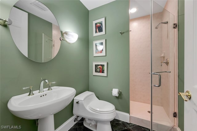 bathroom featuring toilet, a shower with shower door, and sink