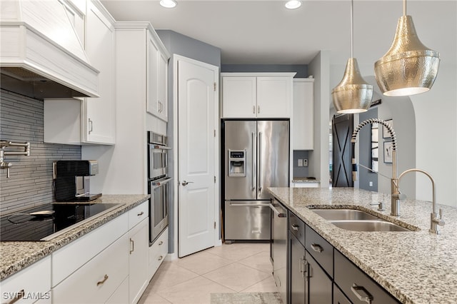 kitchen featuring premium range hood, white cabinetry, light stone countertops, and stainless steel appliances