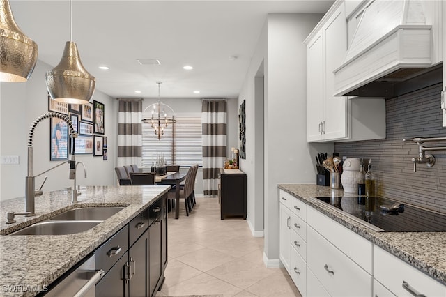 kitchen featuring custom range hood, white cabinetry, hanging light fixtures, and sink