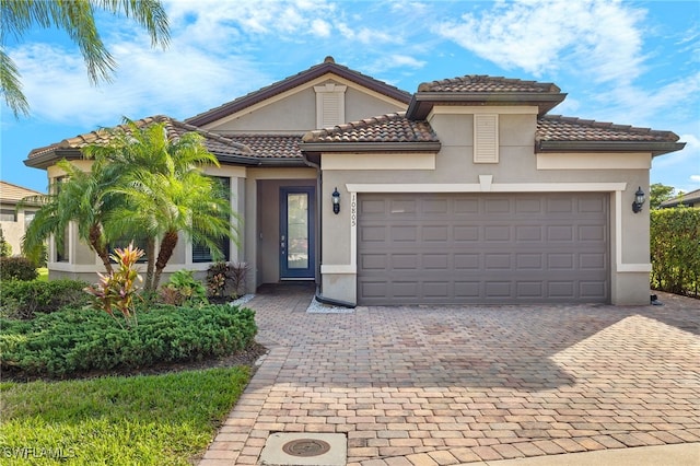 mediterranean / spanish house with an attached garage, decorative driveway, and stucco siding