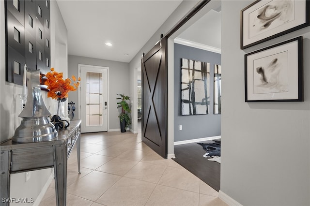 foyer featuring a barn door, crown molding, and light tile patterned flooring