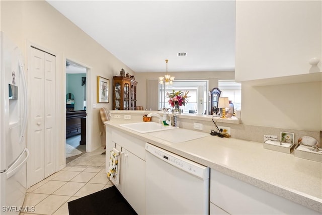 kitchen featuring white appliances, sink, pendant lighting, light tile patterned floors, and a notable chandelier