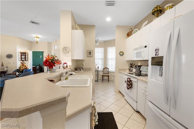 kitchen with kitchen peninsula, white appliances, sink, white cabinets, and light tile patterned flooring