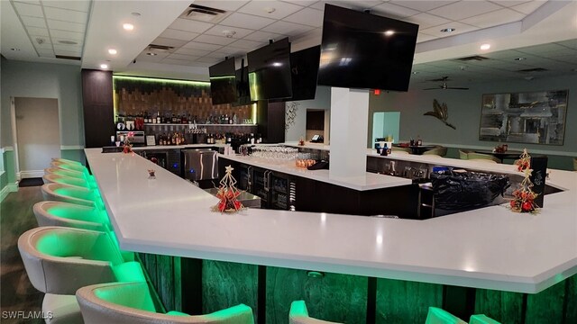 bar with a drop ceiling, ceiling fan, and wood-type flooring