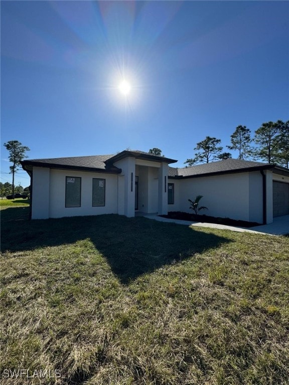 view of front of house with a front lawn, an attached garage, and stucco siding