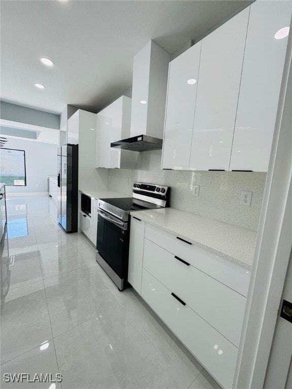 kitchen with white cabinets, wall chimney range hood, appliances with stainless steel finishes, and tasteful backsplash