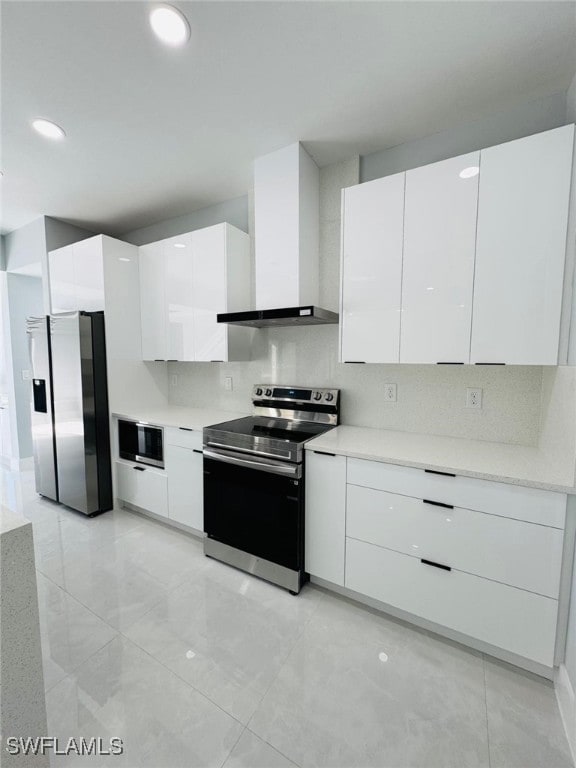 kitchen with tasteful backsplash, white cabinets, wall chimney exhaust hood, and appliances with stainless steel finishes