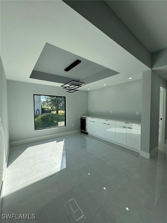 unfurnished living room featuring a tray ceiling and wine cooler