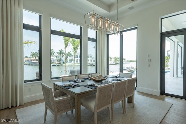 dining room with a water view, light hardwood / wood-style floors, and an inviting chandelier