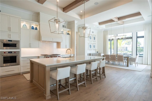 kitchen featuring white cabinets, a breakfast bar, and an island with sink