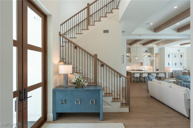 staircase with beam ceiling, sink, french doors, and wood-type flooring