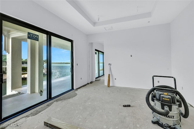 spare room featuring a water view and a raised ceiling