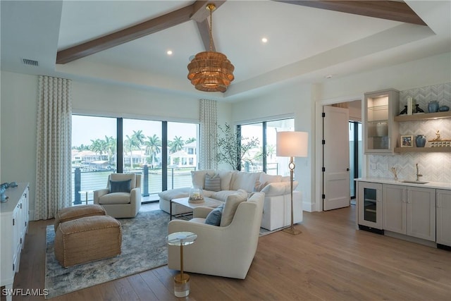 living room featuring beam ceiling, light hardwood / wood-style floors, wine cooler, and sink