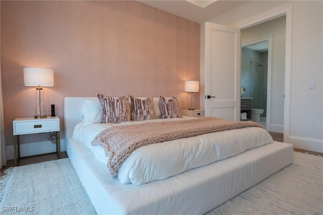 bedroom with ensuite bathroom and hardwood / wood-style flooring