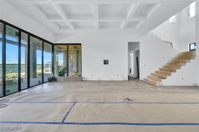 interior space with beam ceiling, a water view, coffered ceiling, and a high ceiling