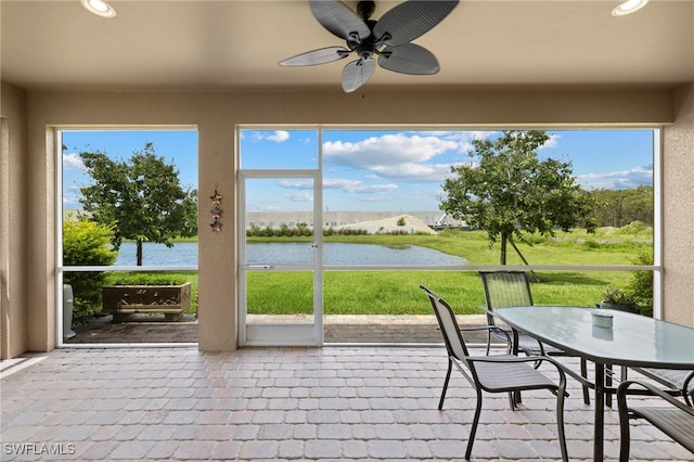 unfurnished sunroom with ceiling fan and a water view