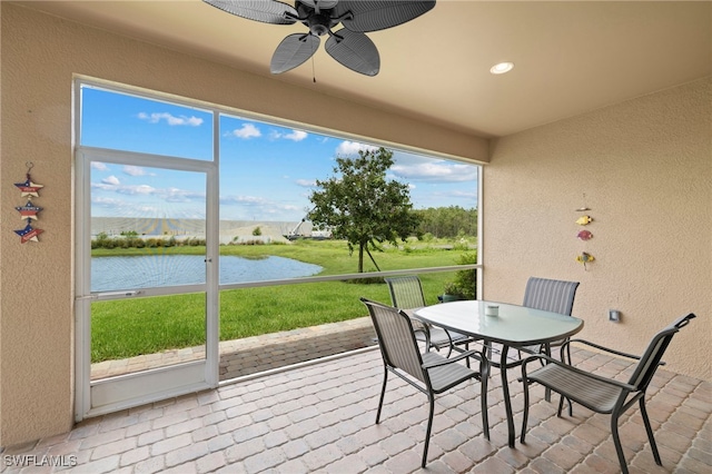 sunroom / solarium featuring ceiling fan and a water view