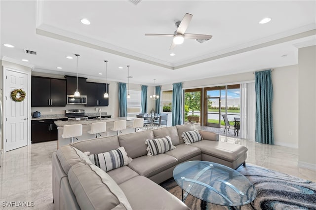 living room with ceiling fan, sink, crown molding, and a tray ceiling