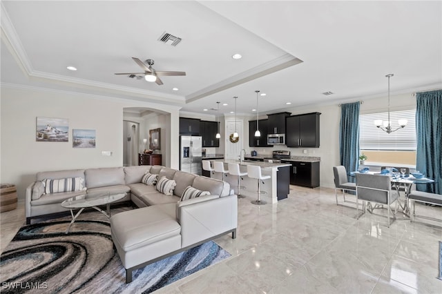 living room featuring ceiling fan with notable chandelier, a raised ceiling, and ornamental molding