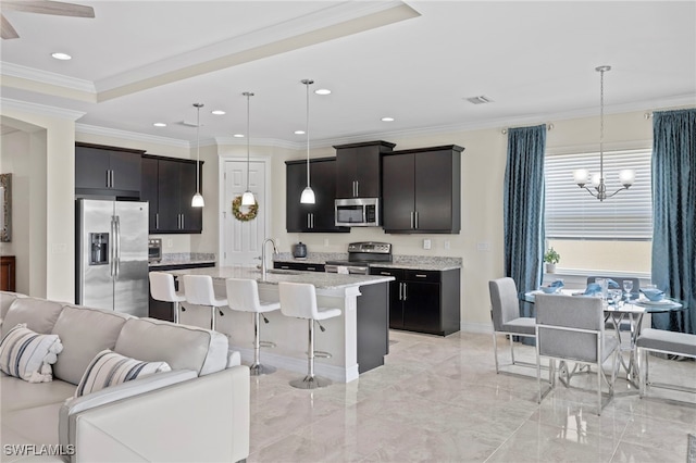 kitchen featuring a center island with sink, stainless steel appliances, hanging light fixtures, and a chandelier