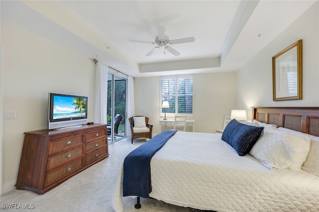 bedroom featuring ceiling fan, a raised ceiling, and light carpet