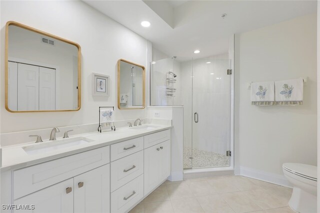 bathroom with tile patterned floors, vanity, toilet, and a shower with door