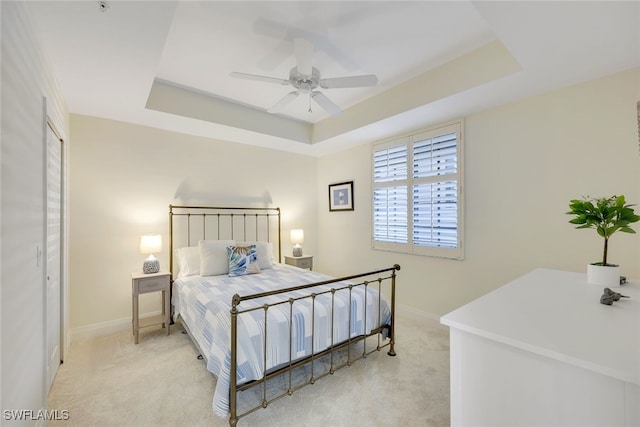 bedroom with baseboards, a tray ceiling, ceiling fan, and light colored carpet