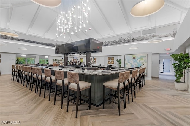 bar featuring beam ceiling, light stone countertops, high vaulted ceiling, and light parquet flooring