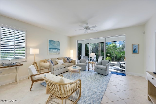 living area with ceiling fan, light tile patterned flooring, a wealth of natural light, and baseboards