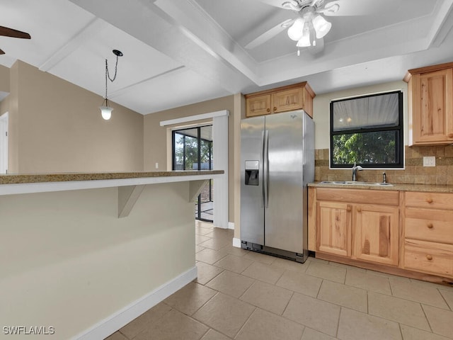 kitchen with a kitchen bar, stainless steel refrigerator with ice dispenser, backsplash, sink, and hanging light fixtures