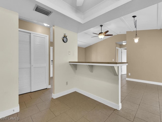 kitchen featuring ceiling fan, kitchen peninsula, pendant lighting, vaulted ceiling, and a kitchen bar