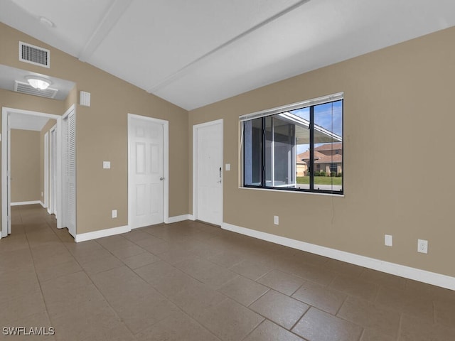 tiled spare room featuring vaulted ceiling