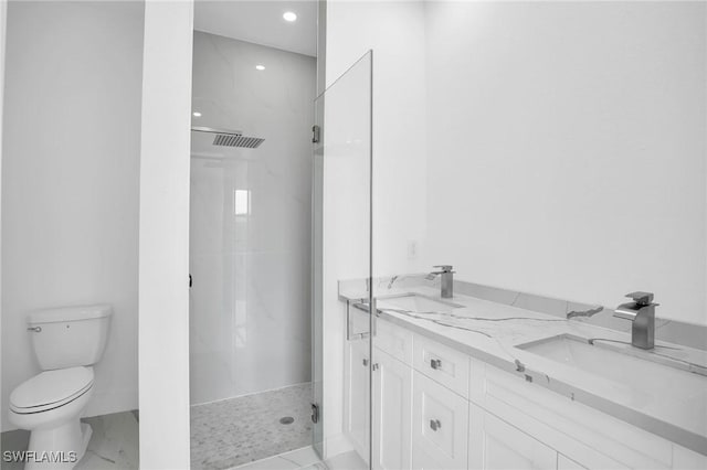 bathroom featuring a tile shower, vanity, and toilet