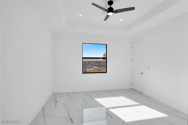 spare room with a raised ceiling and ceiling fan