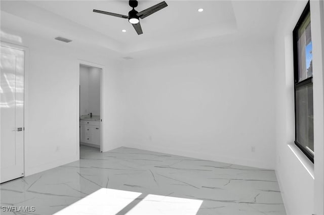 empty room featuring ceiling fan and a tray ceiling