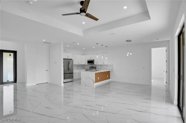 kitchen with ceiling fan, hanging light fixtures, white cabinets, a kitchen island, and appliances with stainless steel finishes