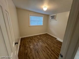 unfurnished room with dark wood-type flooring, a wall unit AC, and vaulted ceiling