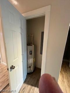 hallway featuring water heater, electric panel, and light hardwood / wood-style floors