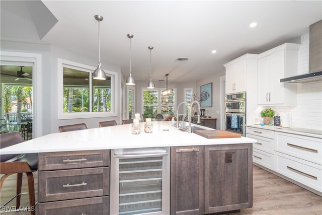 kitchen with double oven, beverage cooler, visible vents, white cabinetry, and backsplash