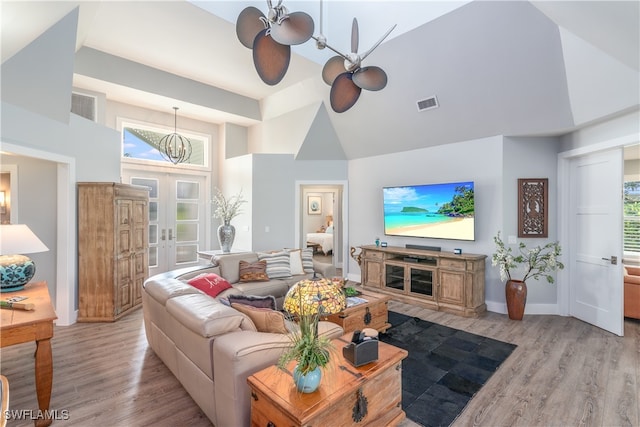 living room featuring high vaulted ceiling, light wood-style flooring, visible vents, and french doors