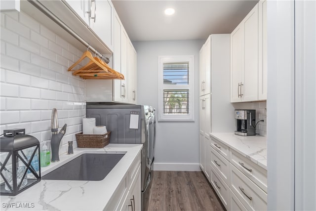 kitchen with tasteful backsplash, washer and clothes dryer, dark wood-style flooring, white cabinetry, and a sink