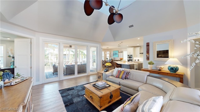 living room featuring lofted ceiling, ceiling fan, visible vents, and wood finished floors