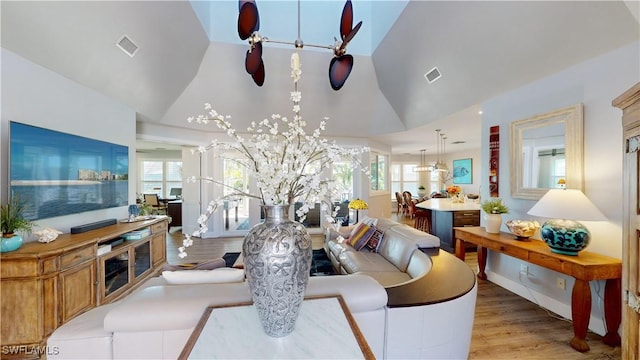 living area with visible vents, plenty of natural light, and wood finished floors