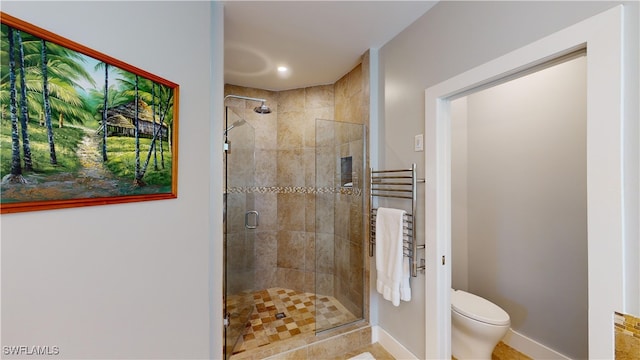 bathroom with a stall shower, toilet, and baseboards