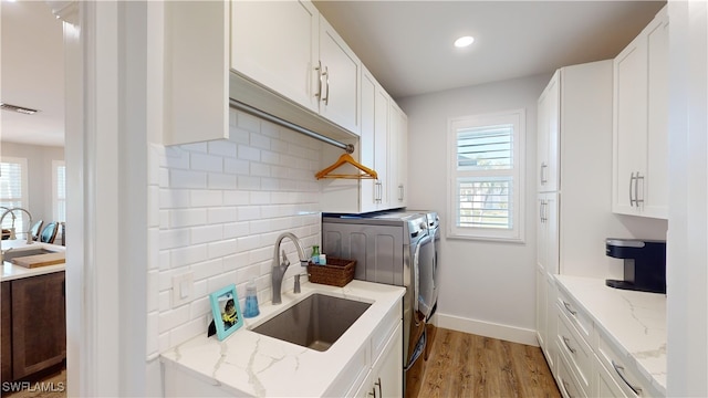 kitchen featuring tasteful backsplash, visible vents, independent washer and dryer, light wood-type flooring, and a sink