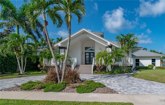 view of front of property with covered porch, french doors, and a front lawn