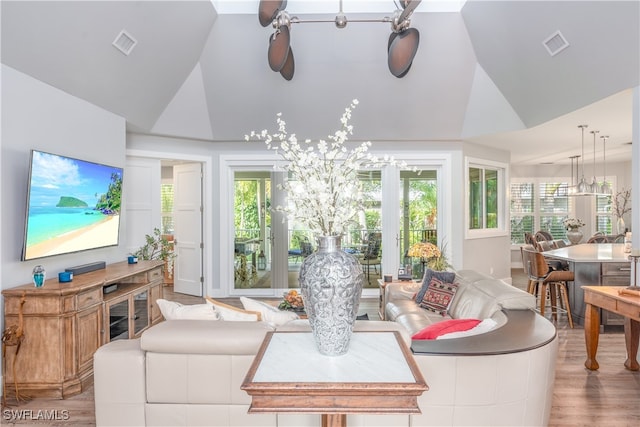 living area with high vaulted ceiling, wood finished floors, and visible vents